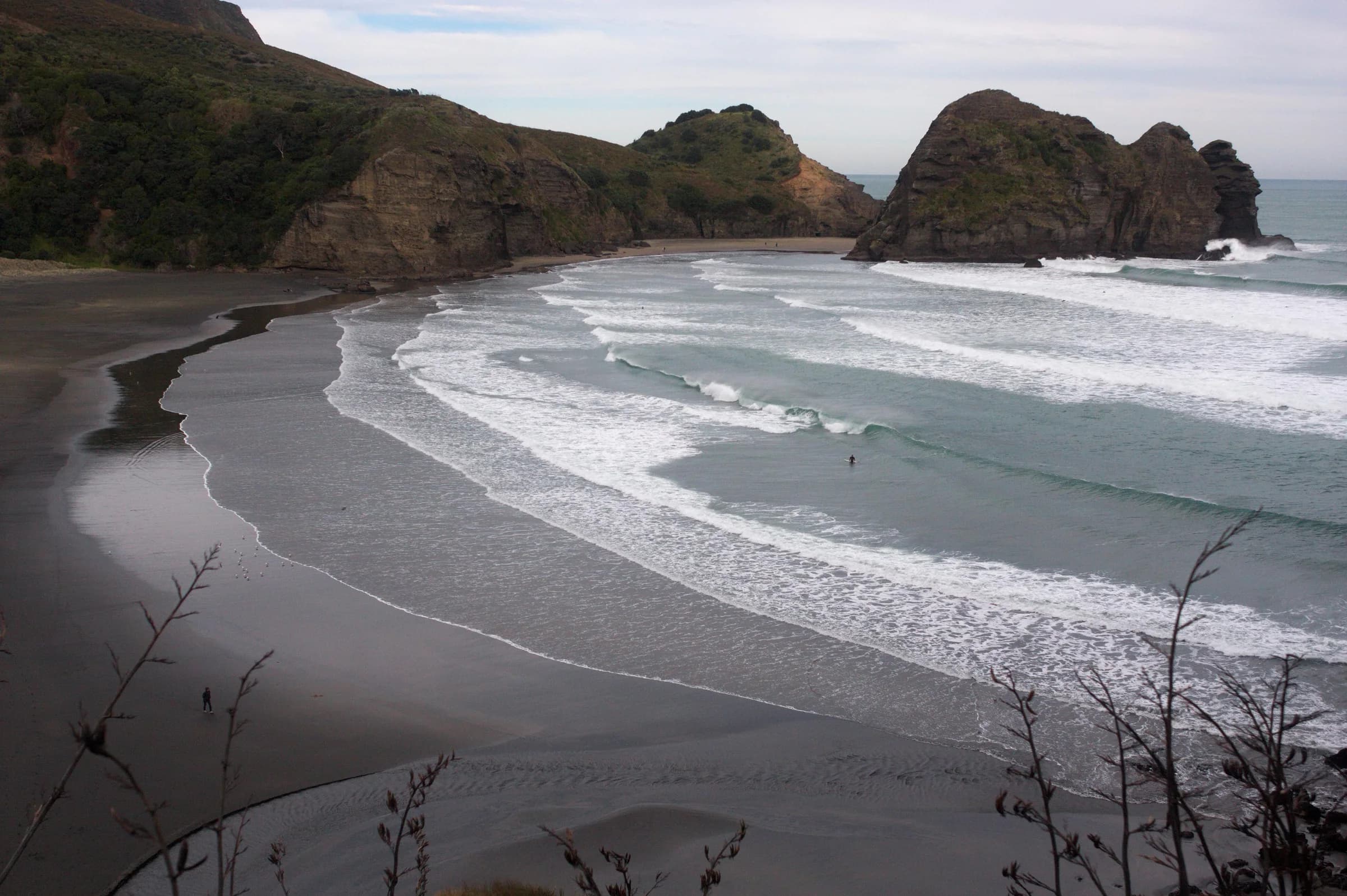 Piha Beach on Auckland's west coast with black sand, surf, and rocky headlands