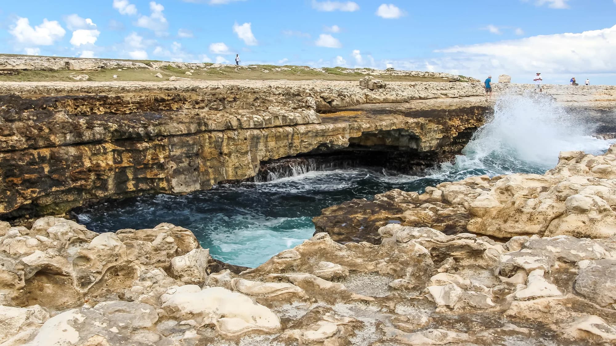 Sea spray breaking across the limestone coast at Devil's Bridge National Park in Antigua