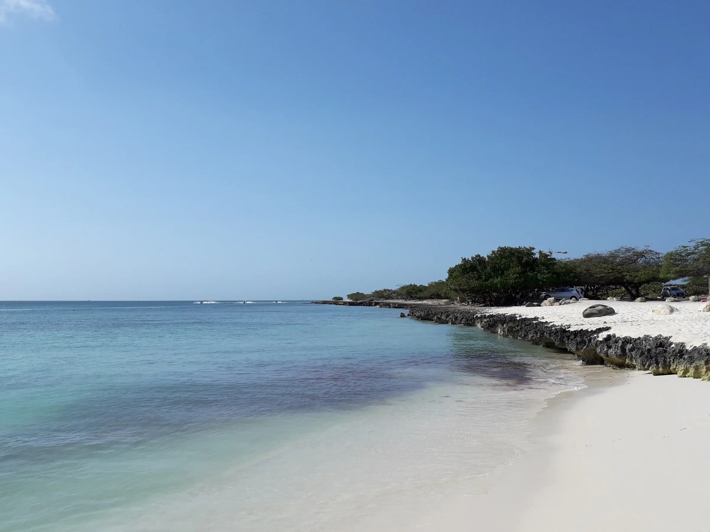 Calm turquoise water and white sand curving along Eagle Beach in Aruba