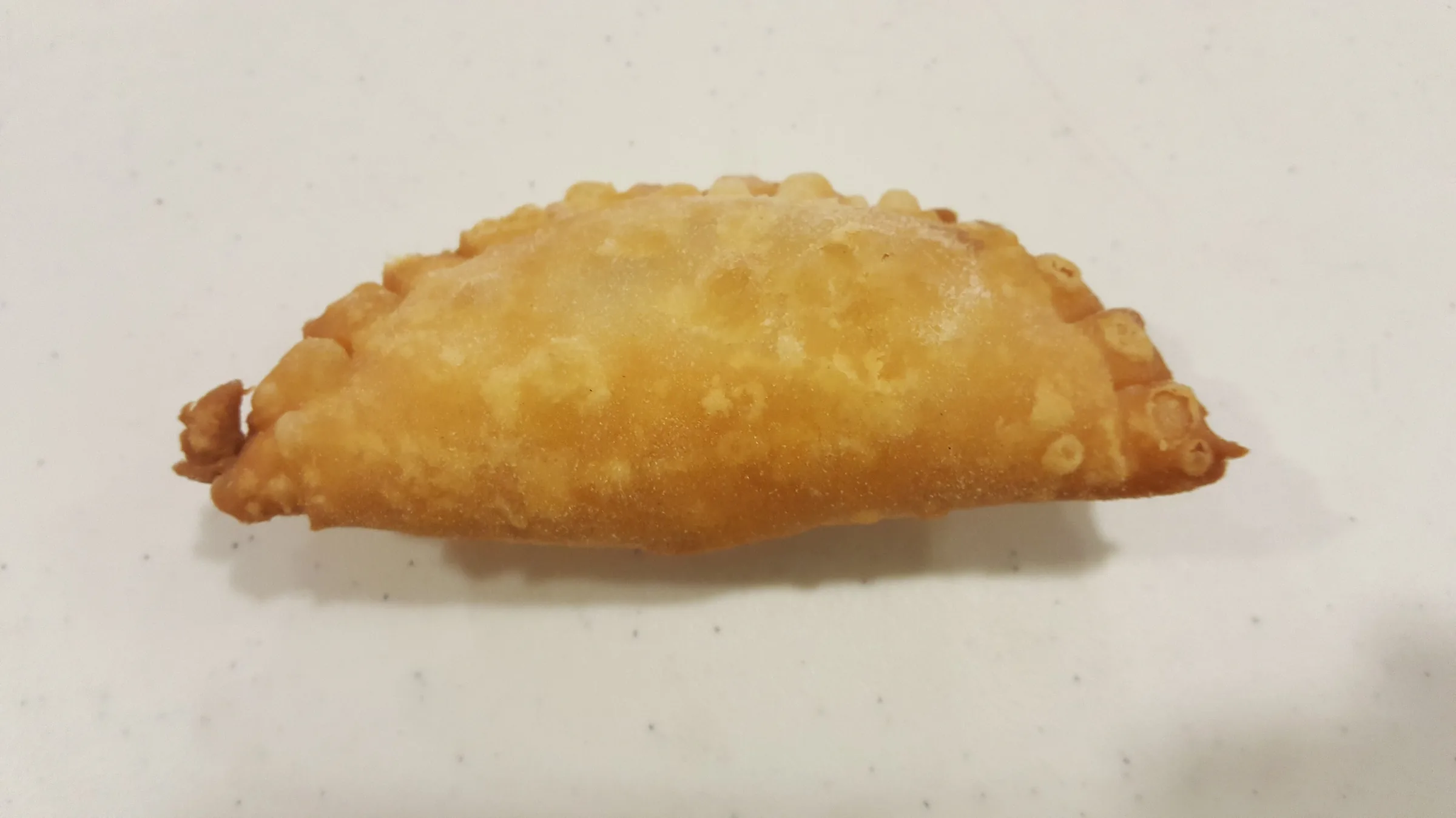 Golden fried Aruban pastechi pastry on a white plate