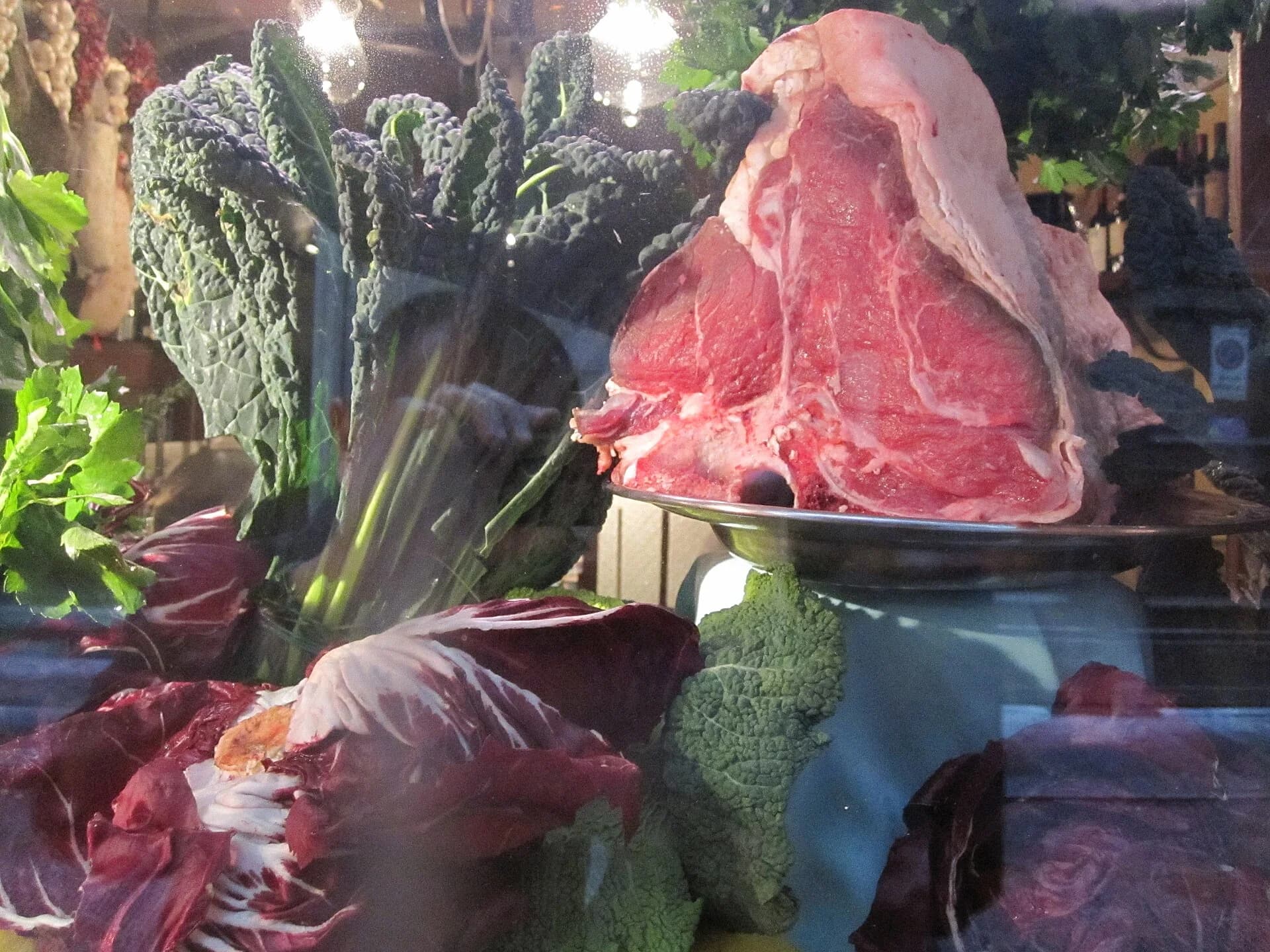Raw bone-in bistecca alla fiorentina displayed with Tuscan vegetables in Florence