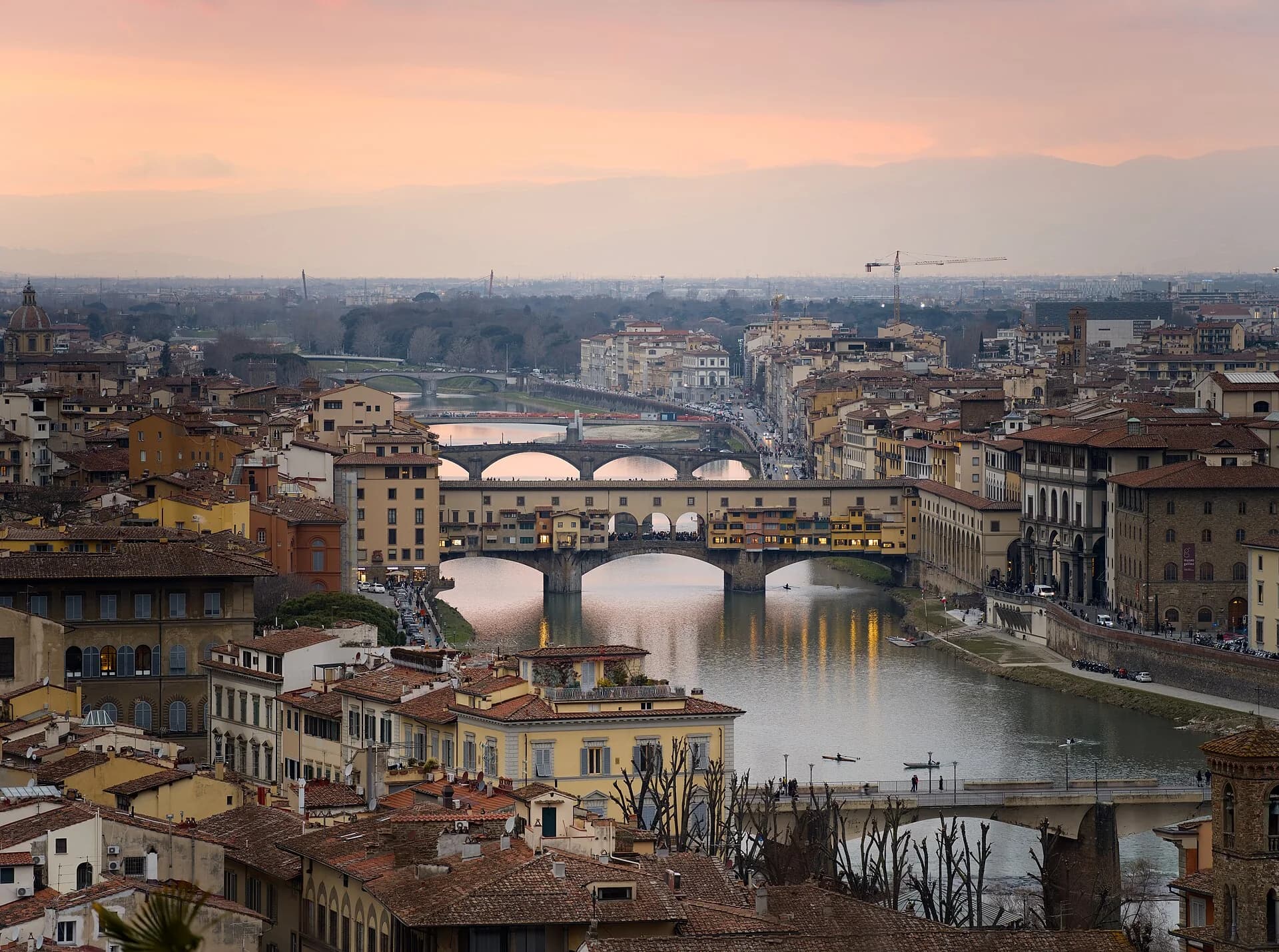 Ponte Vecchio crossing the Arno at sunset beneath Florence's historic skyline