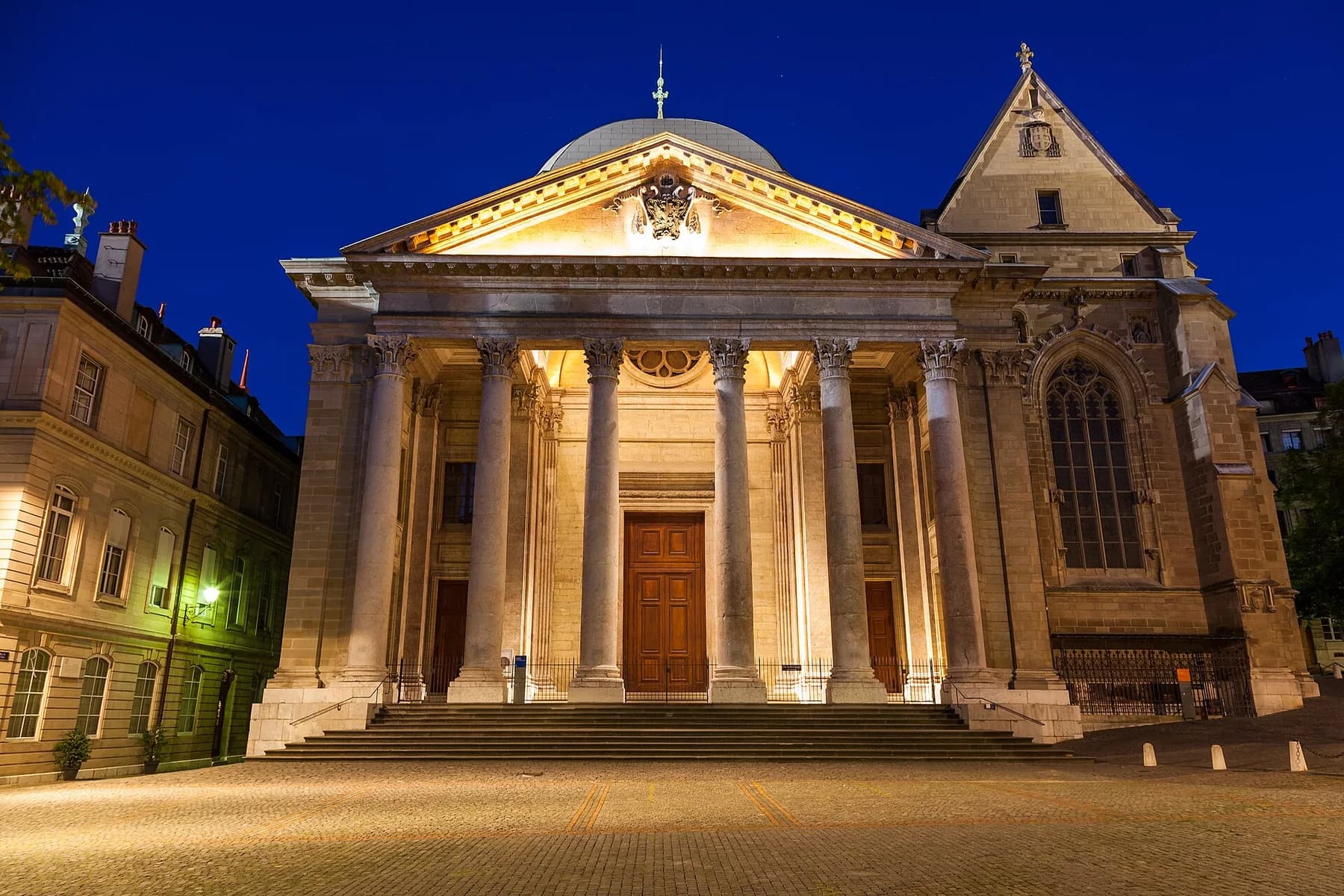 Illuminated neoclassical façade of Saint Pierre Cathedral in Geneva's Old Town at night